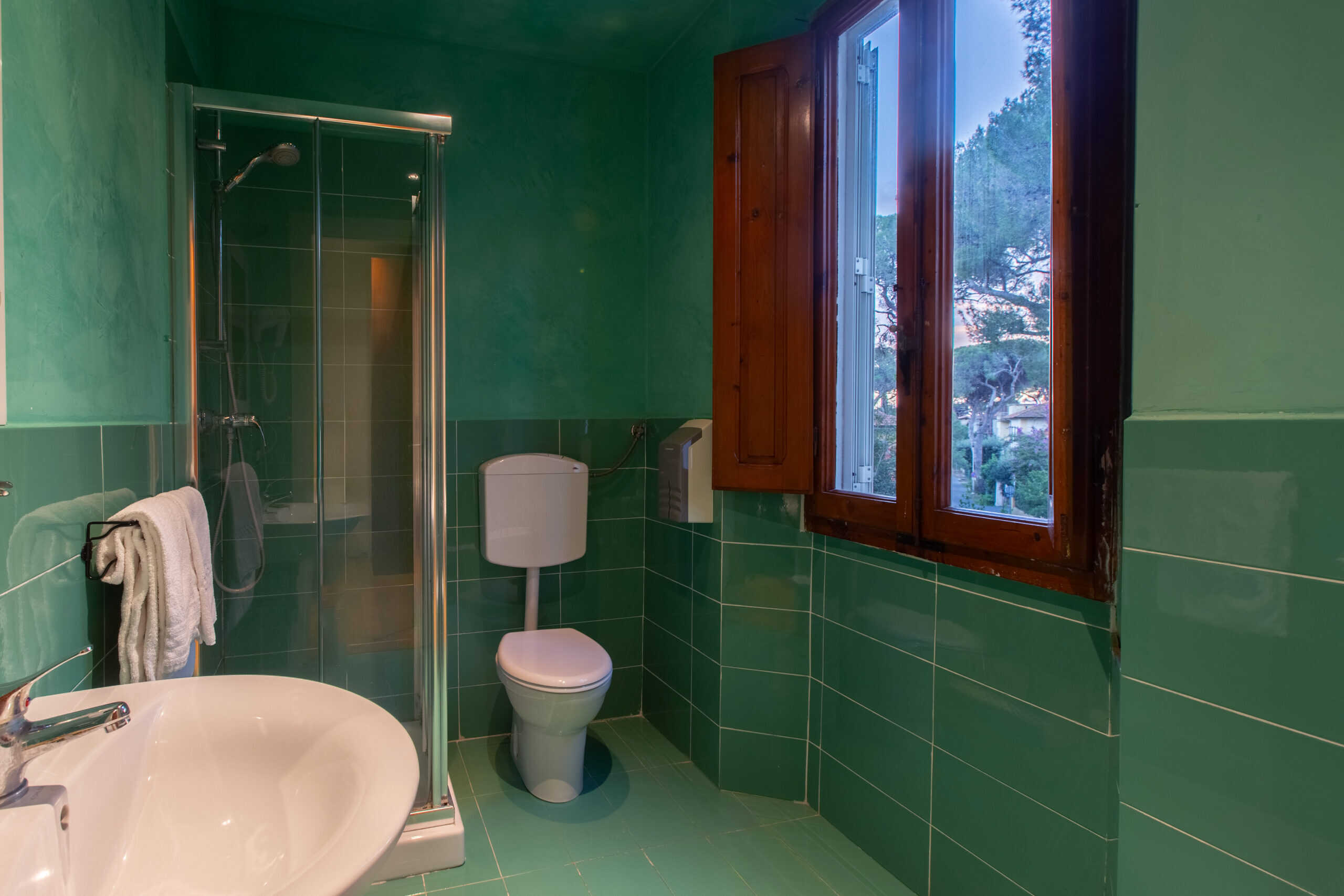 bagno con doccia e pareti di colore verde acqua della camera singola dell'Hotel Guerrini