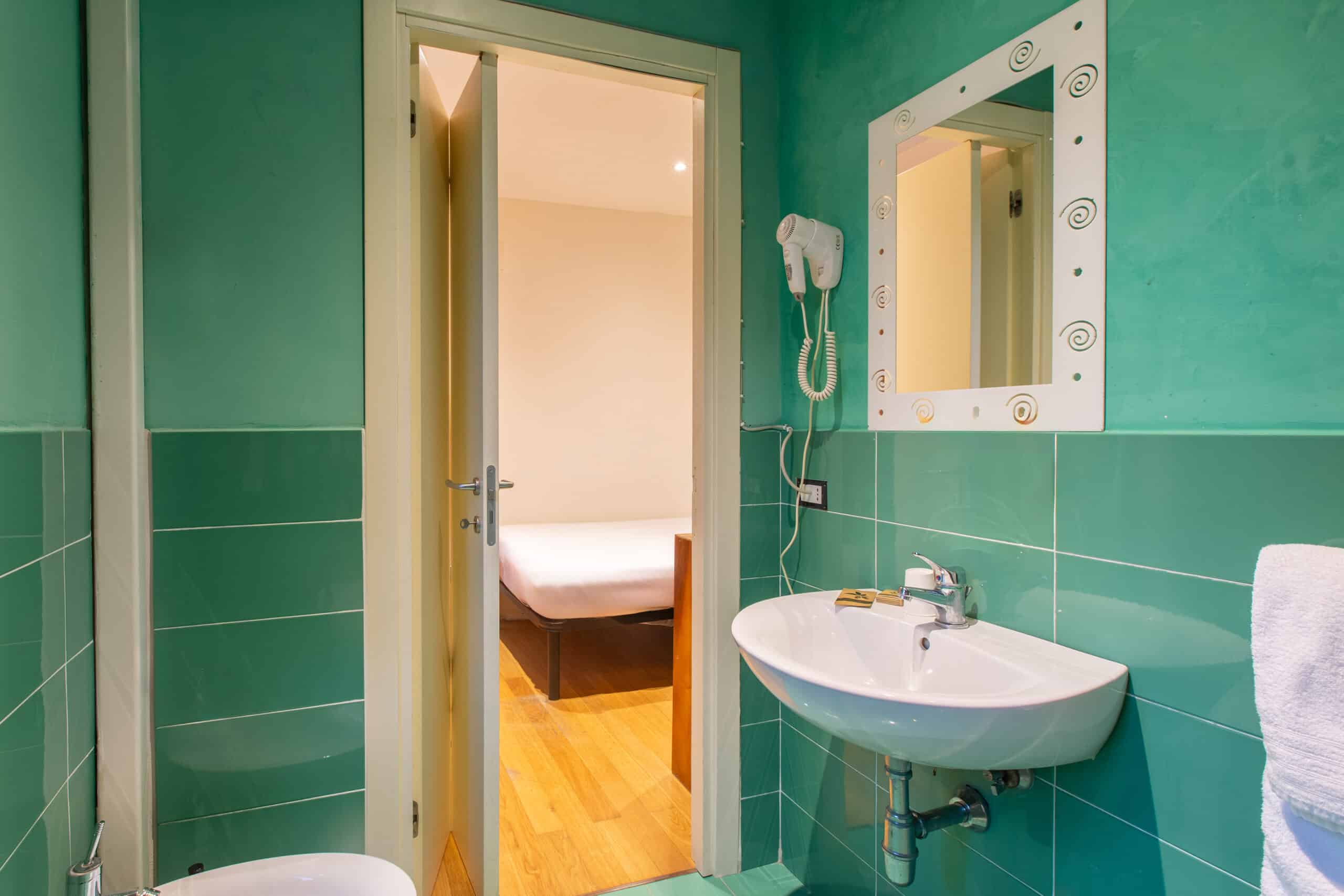bagno con lavandino e pareti di colore verde acqua della camera singola dell'Hotel Guerrini
