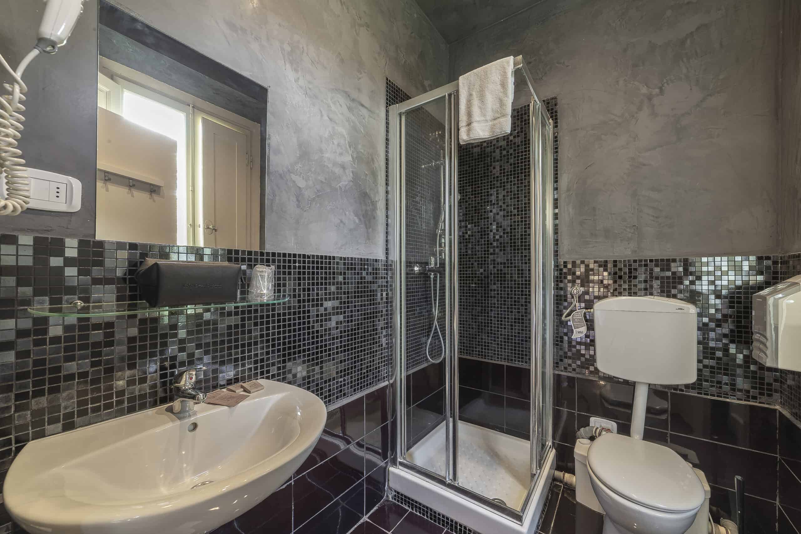 Bagno con piastrelle nere con doccia e lavandino, Hotel Guerrini